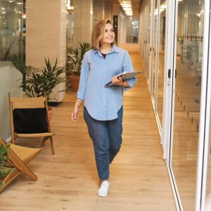 Eine junge Frau geht mit Unterlagen in der Hand über einen Büroflur.