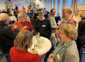 Teilnehmende an Stehtischen und in kleinen Gruppen tauschen sich aus. 