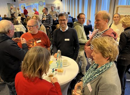 Teilnehmende an Stehtischen und in kleinen Gruppen tauschen sich aus. 